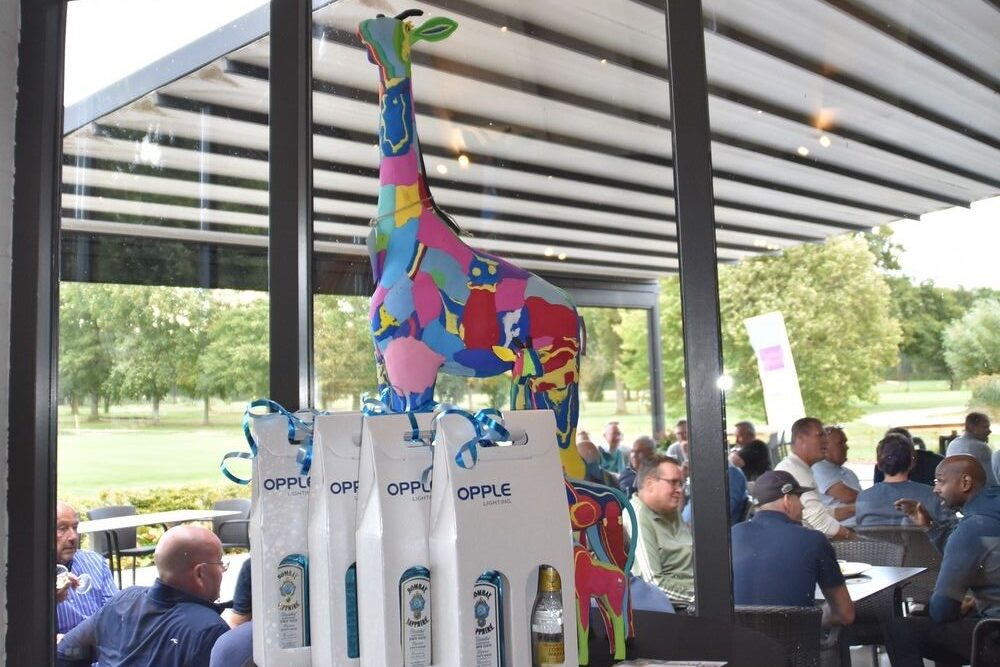 Giraffe beeld van Pinidraf Foundation op tafel met een aantal prijzen voor de Pinidraf Golfcup.